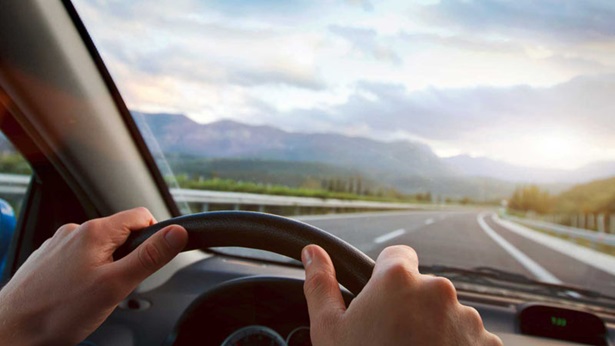Mãos no volante a conduzir um carro numa autoestrada com curva.